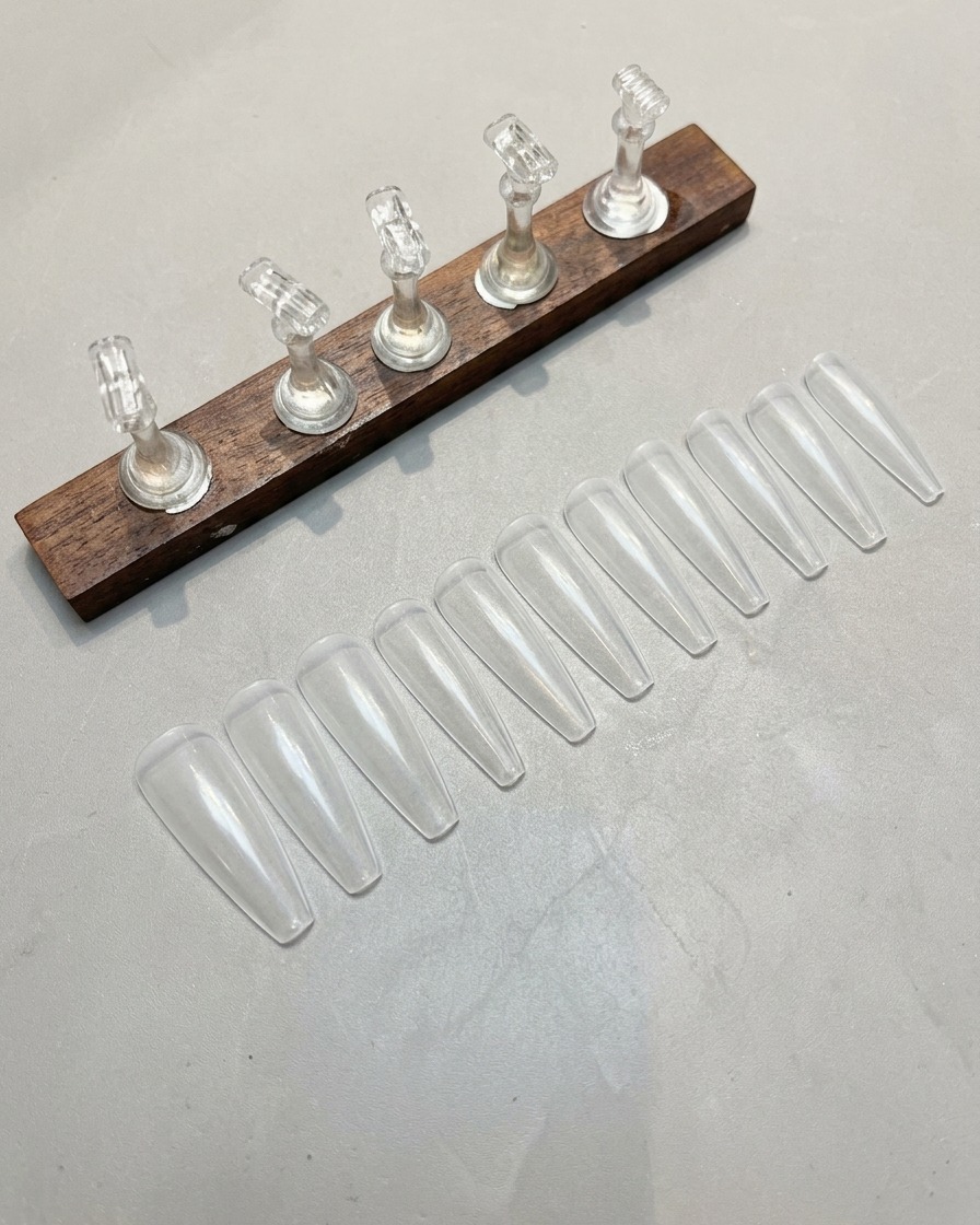 Main utilisant une lime pour poncer délicatement la surface dune capsule transparente.