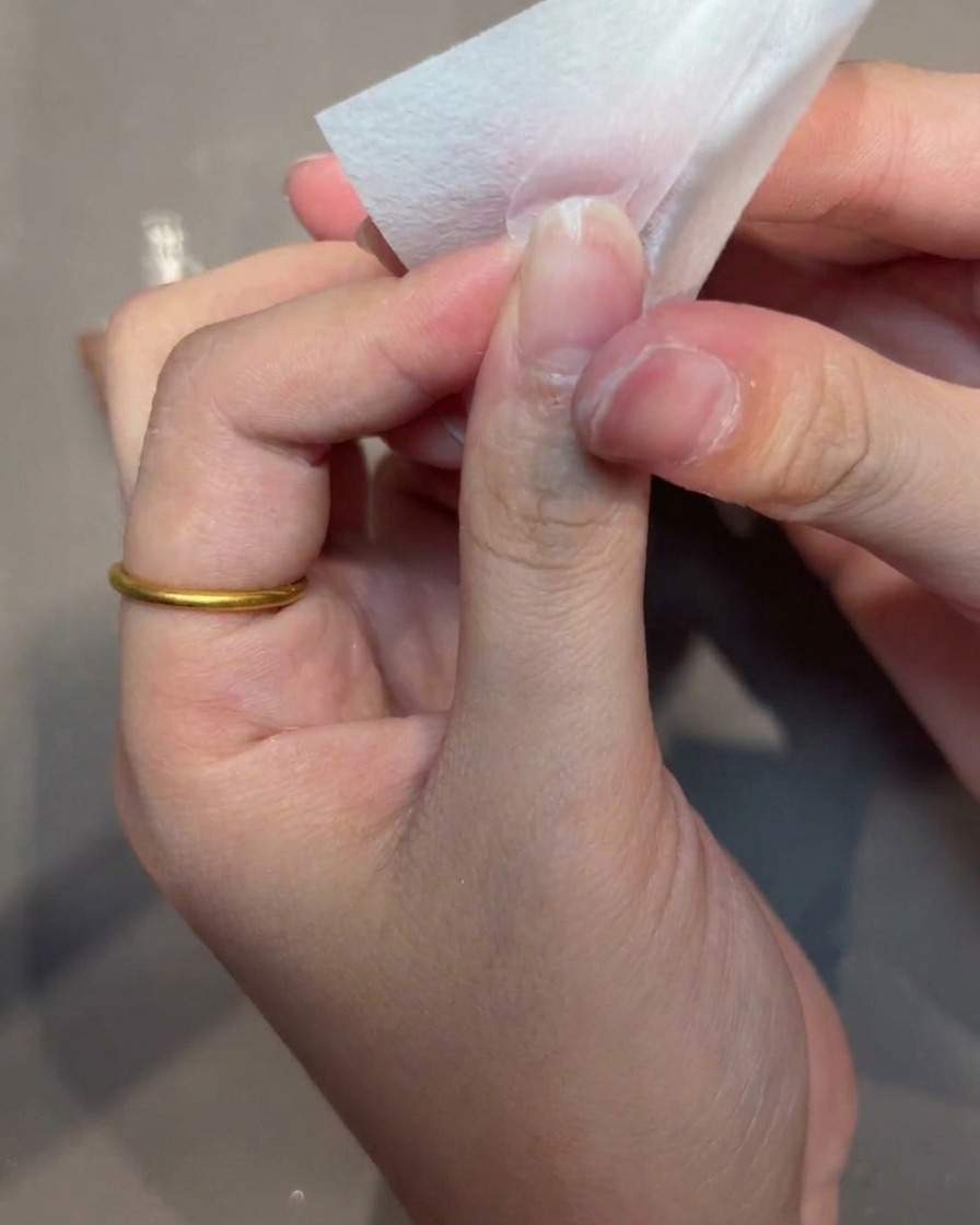 Main utilisant un coton non pelucheux pour nettoyer la surface dune capsule.