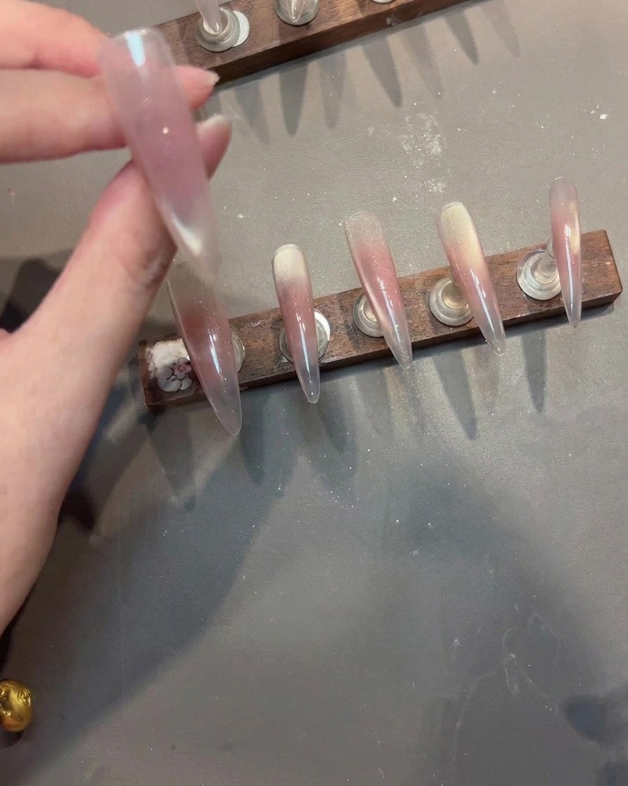 Tampon de stamping pressant un motif de dentelle blanche sur un ongle rose.