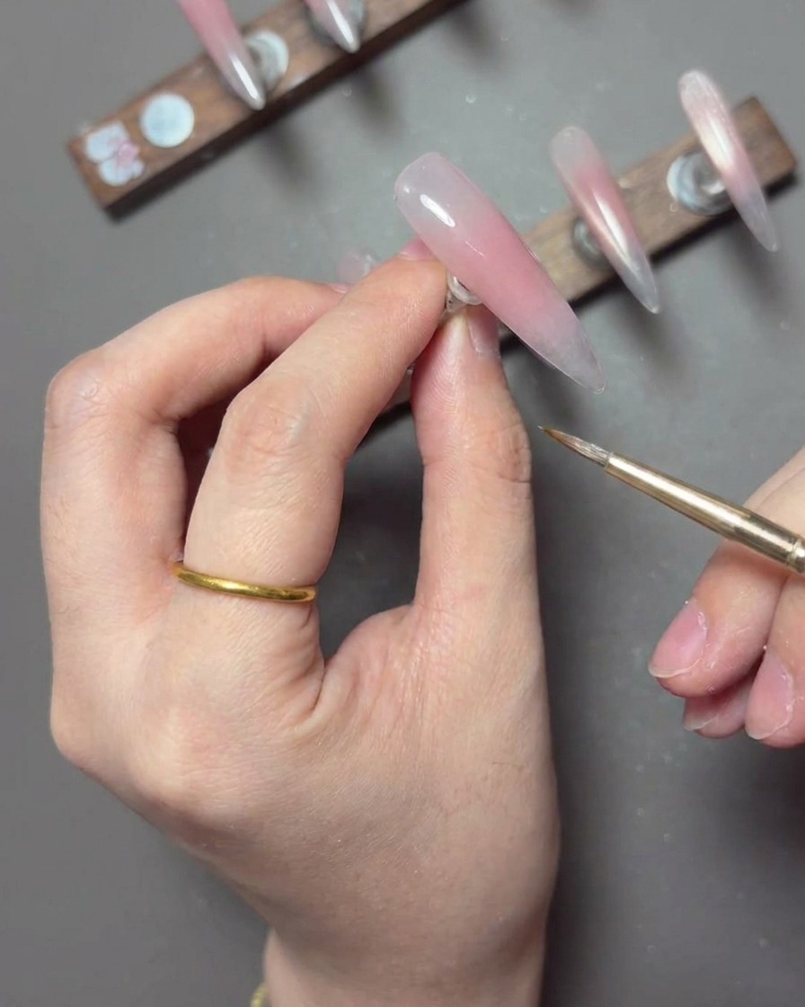 Pinceau liner utilisant du spider gel blanc pour ajouter des détails fins sur un ongle.