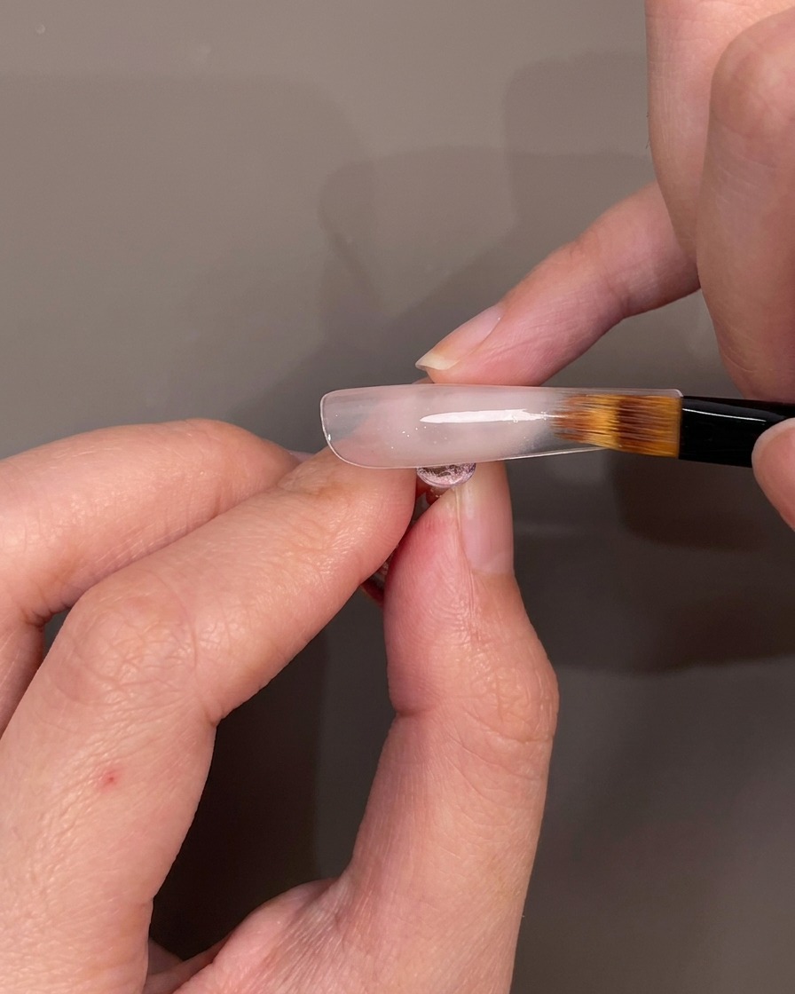 Un pinceau estompant le gel nude vers le bas pour créer un effet ombré.