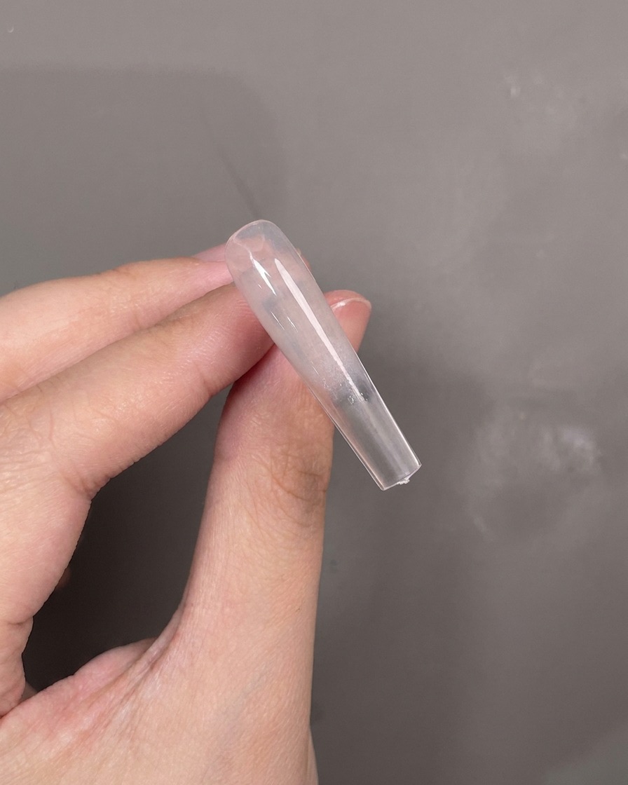 Un outil en silicone bleu étalant du gel texture blanc horizontalement au centre de longle.