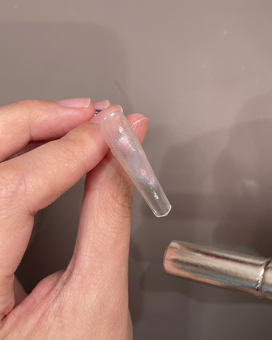 Une main tenant la capsule tandis quun aimant survole le gel humide pour créer le reflet.