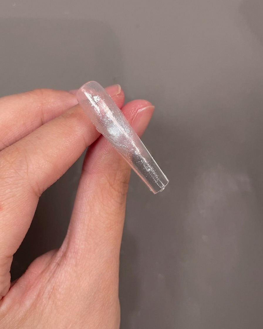 Le dessous dune capsule transparente avec une petite fleur bleue placée dans une couche de gel humide.