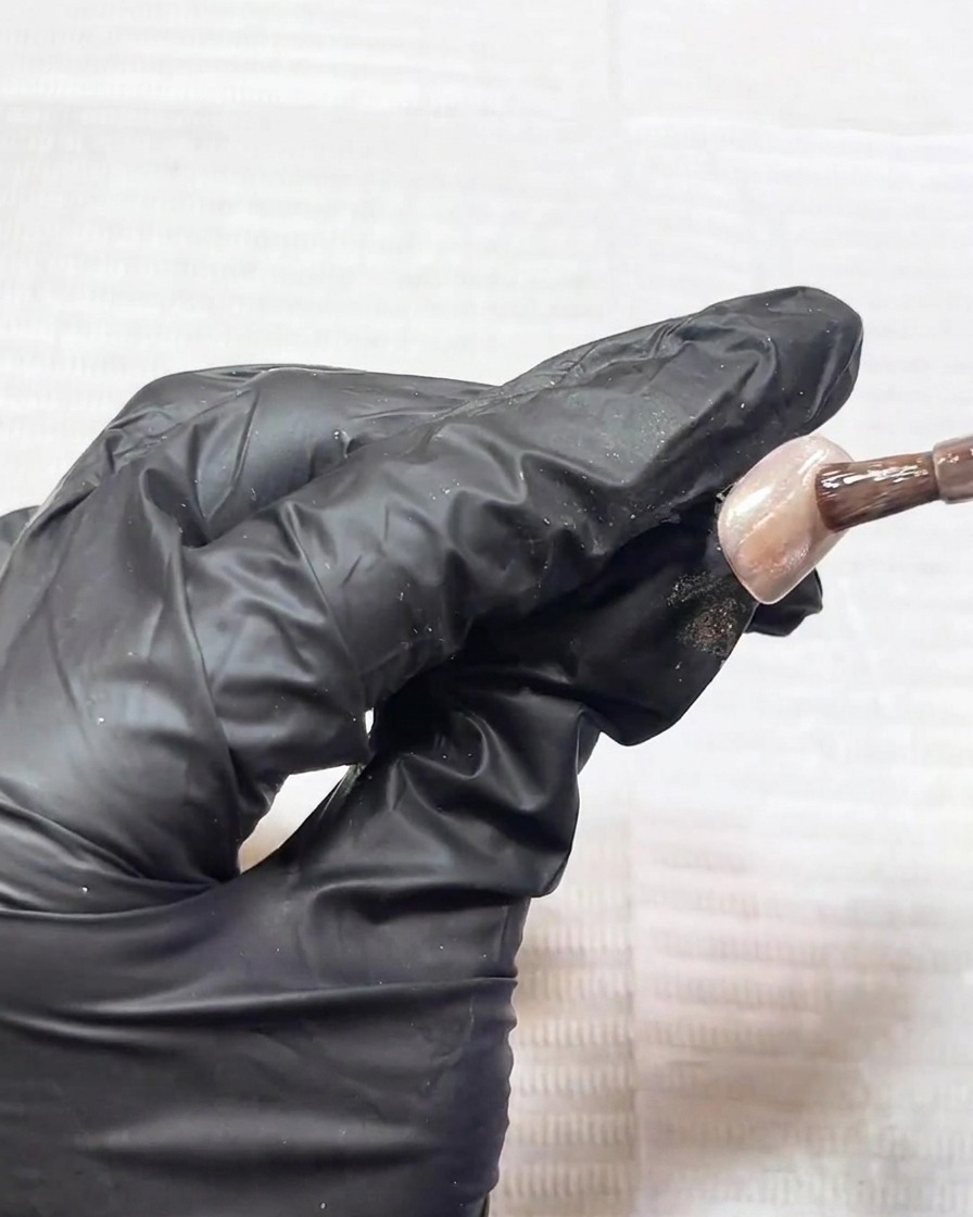 Gros plan dun aimant tenu au-dessus dun ongle, montrant les particules métalliques en mouvement.