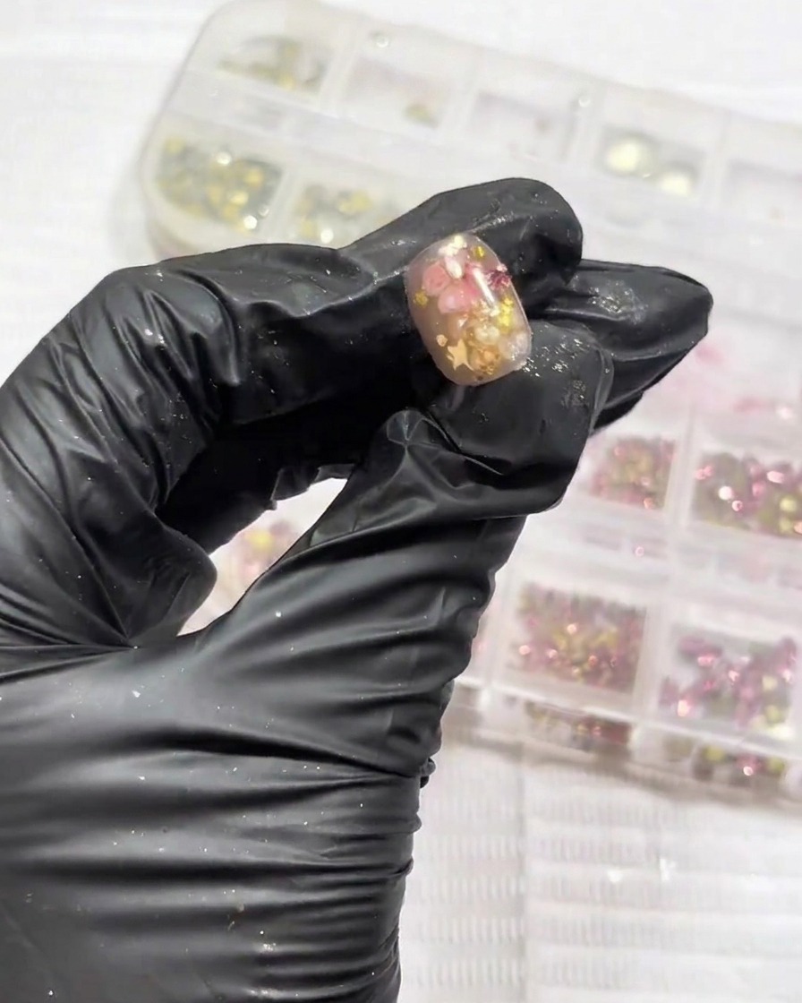 Gros plan sur de petits strass étincelants placés dans le coin dun ongle décoré.