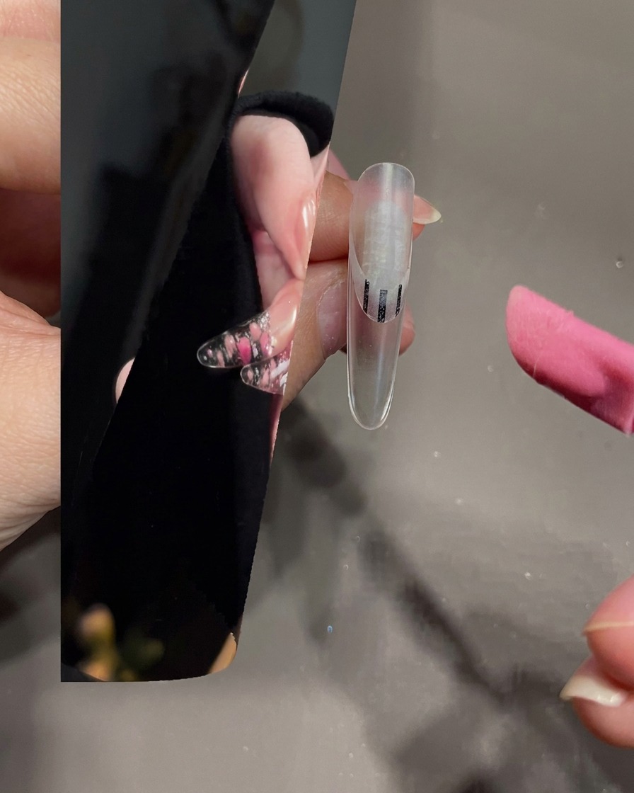 Un pinceau à nail art étalant du gel blanc sur la pointe dun ongle transparent.