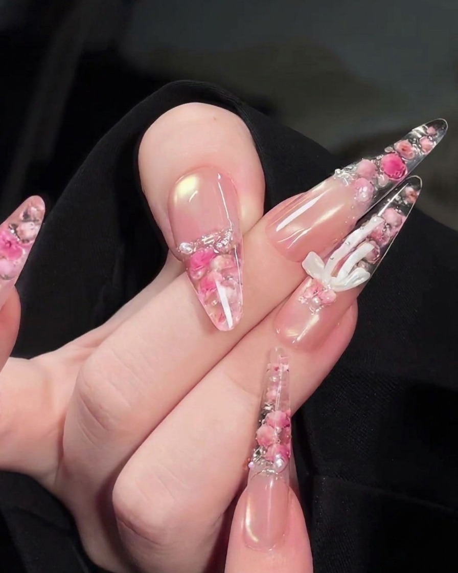 Un pinceau de précision plaçant de minuscules perles blanches et des strass sur le design floral au dos de longle.