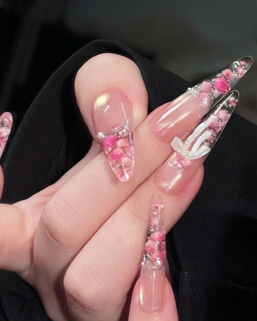 Une main positionnée sous une lampe à ongles UV, avec le design de roses et perles encapsulé visible sur les ongles.