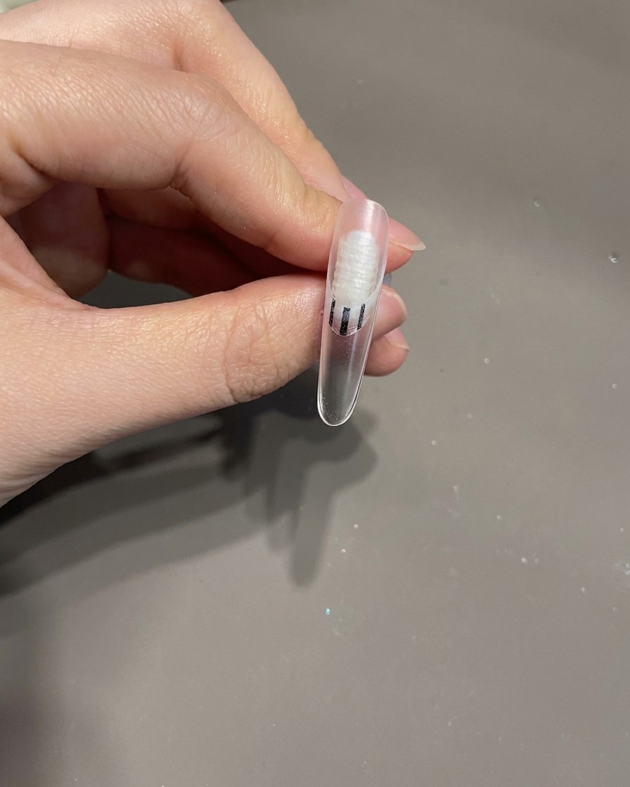 Un ongle fini avec un nœud 3D et des lignes blanches tourbillonnantes à lintérieur dune lampe UV pour le processus de catalyse finale.