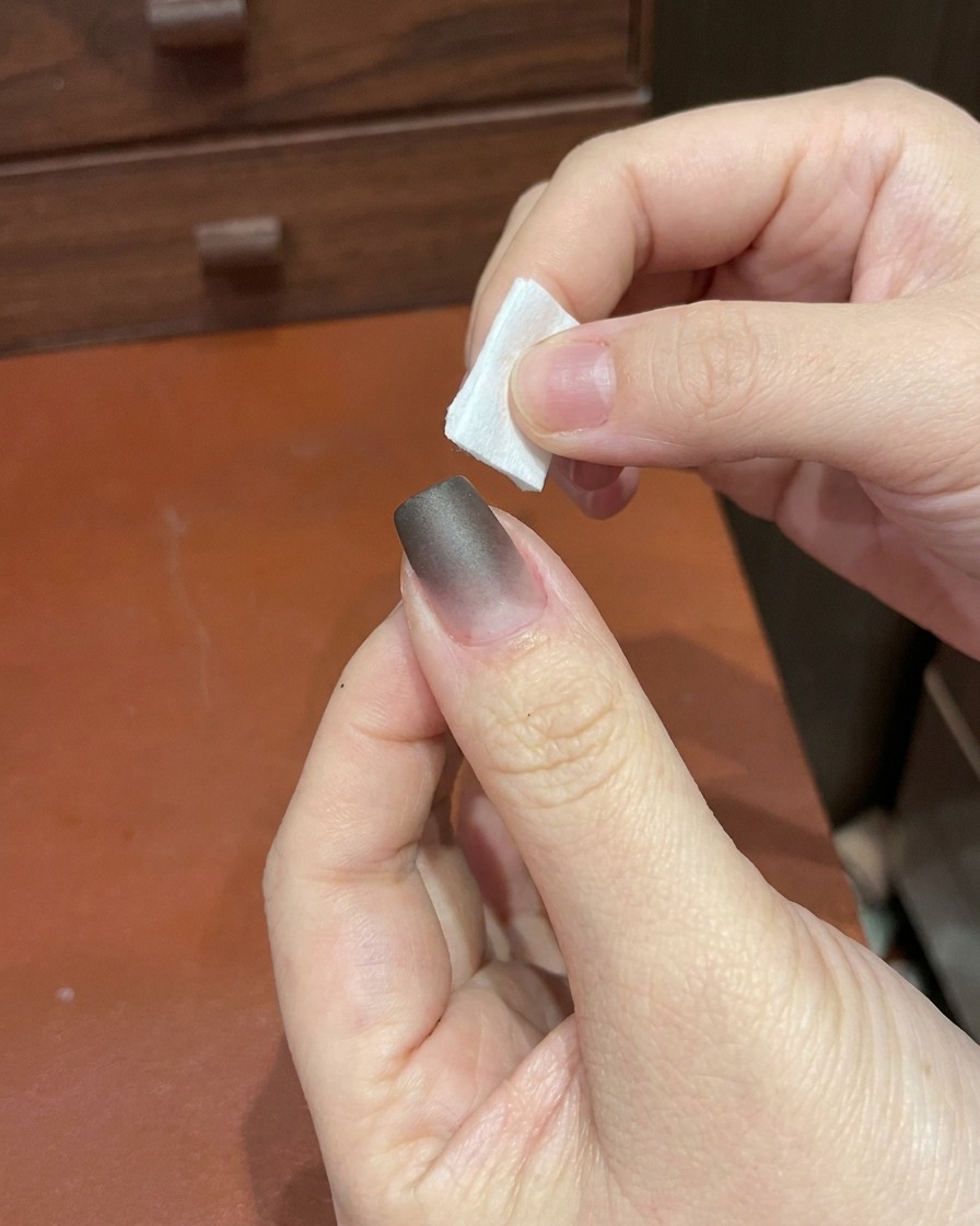 Une main plaçant un doigt sous une petite lampe UV/LED portable pour ongles.