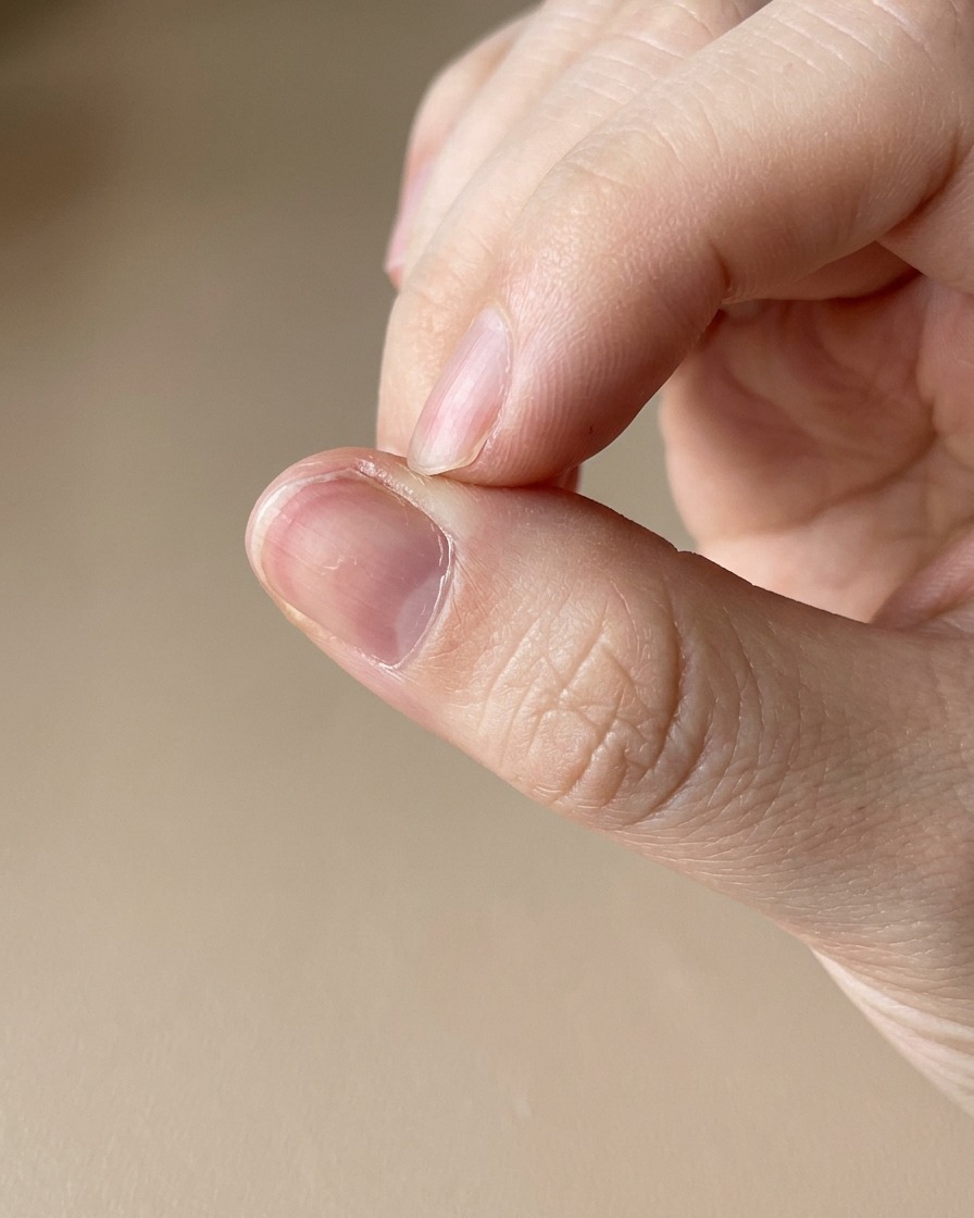Gros plan dun stylo dhuile à cuticules appliqué sur la peau entourant un ongle fraîchement manucuré.