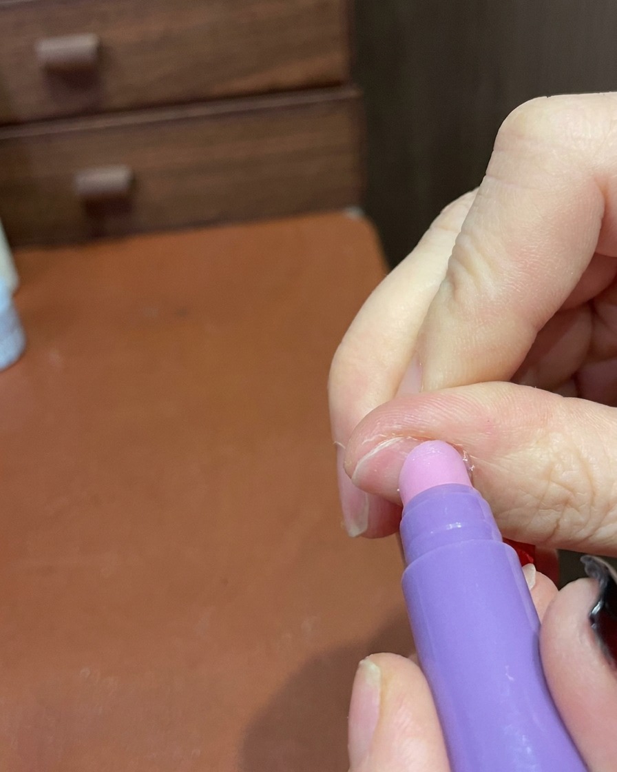 Gros plan dun stylo de soin utilisé pour lisser doucement la surface et les contours dune manucure terminée.
