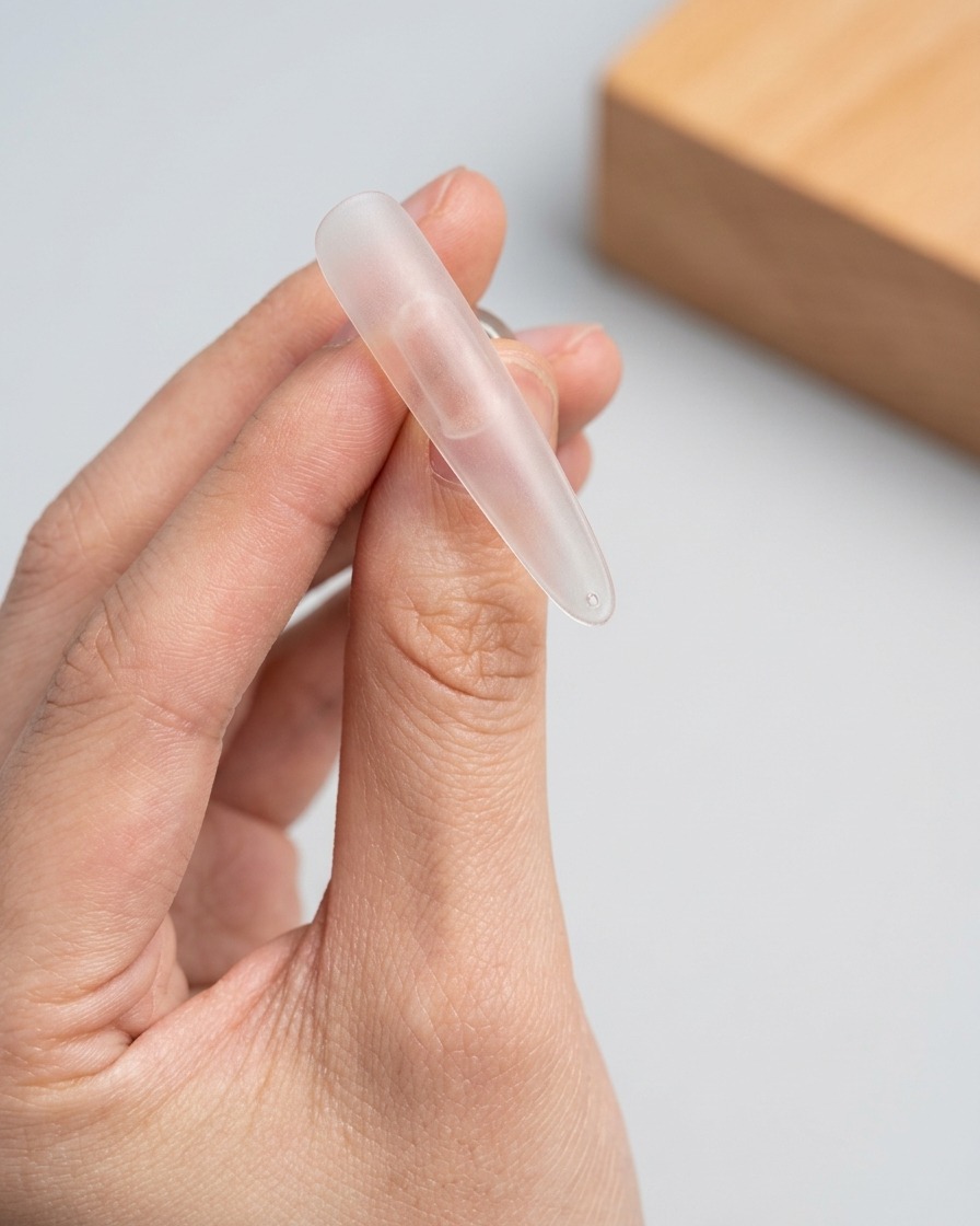 Un pinceau appliquant une couche de gel cat-eye scintillant sur la partie supérieure dun embout dongle transparent.