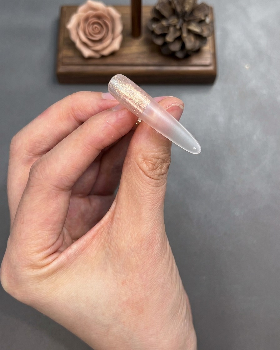 Un pinceau estompant les bords du gel cat-eye appliqué sur un ongle pour créer une transition douce.