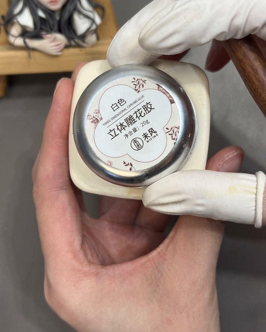 Un outil tenant une petite bille de gel de sculpture 3D blanc contre la paume de la main.