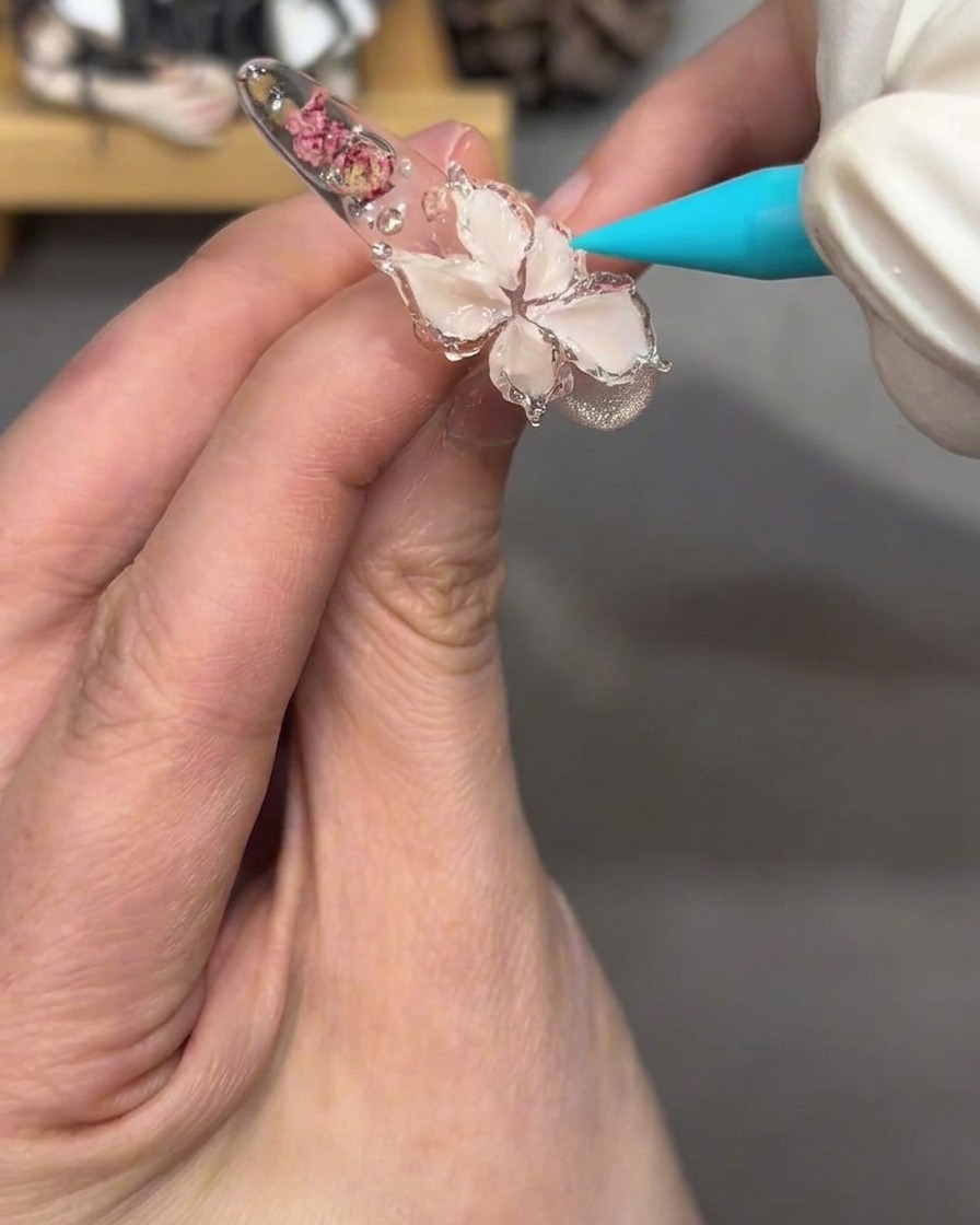 Gros plan du design floral sur longle, paraissant brillant et translucide après application dun gel jelly transparent.