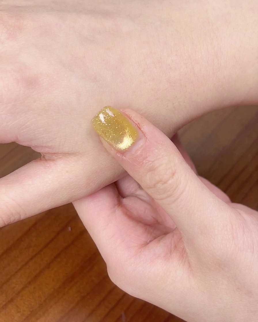 Une main sous une lampe UV/LED en train de catalyser le vernis gel.