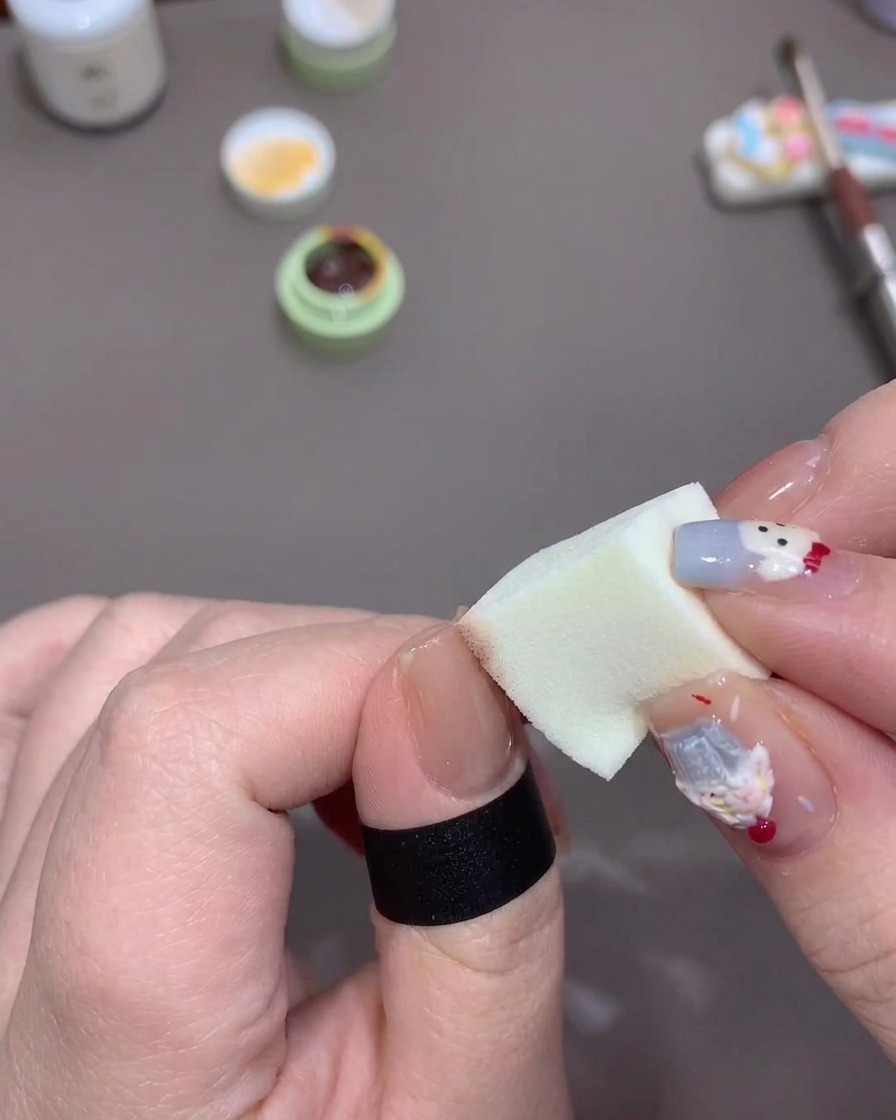 Une main tapotant une éponge chargée de gel orange sur le bord libre dun ongle pour créer un fondu.