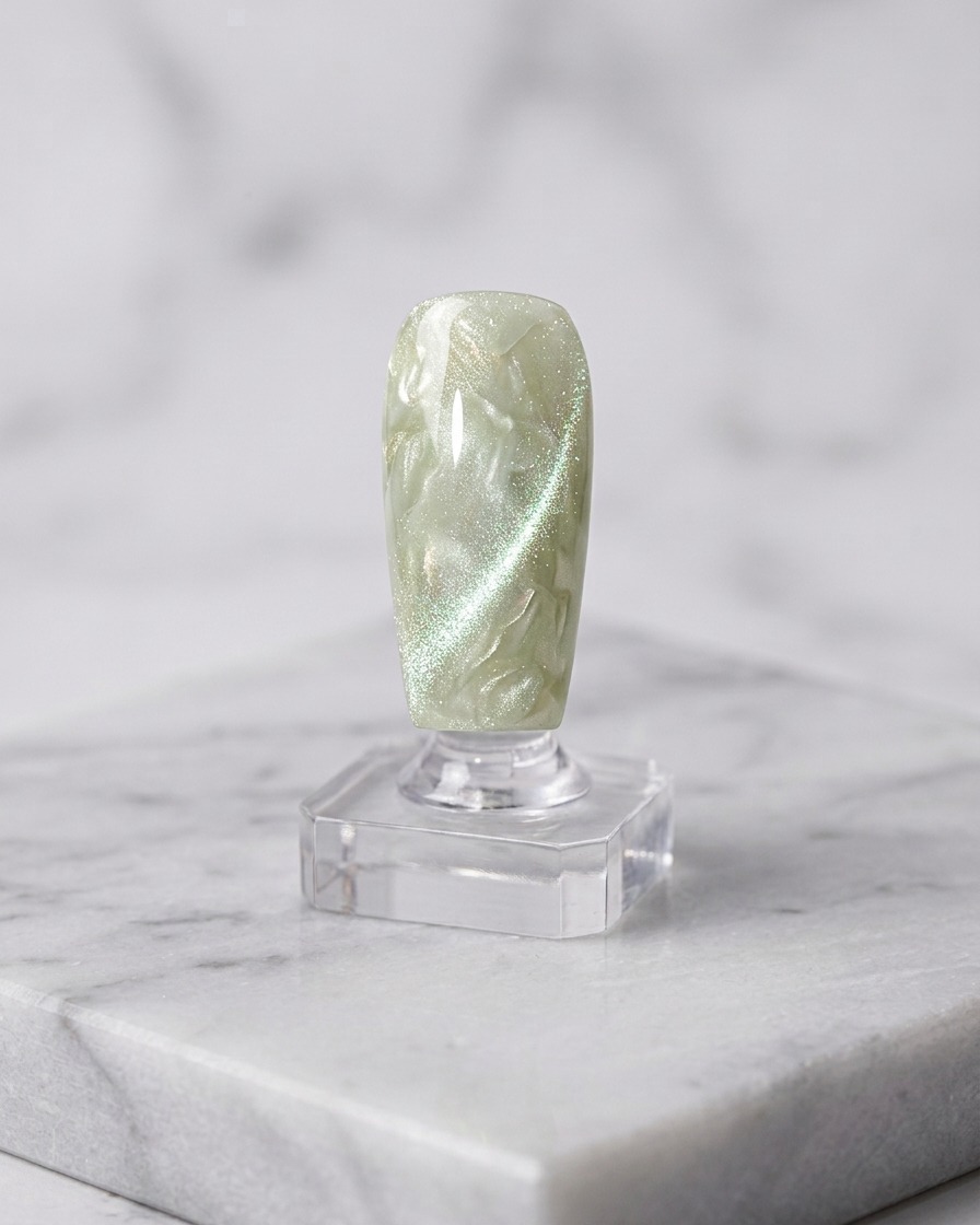 Un pinceau appliquant une deuxième couche de gel cat-eye sur la base catalysée.