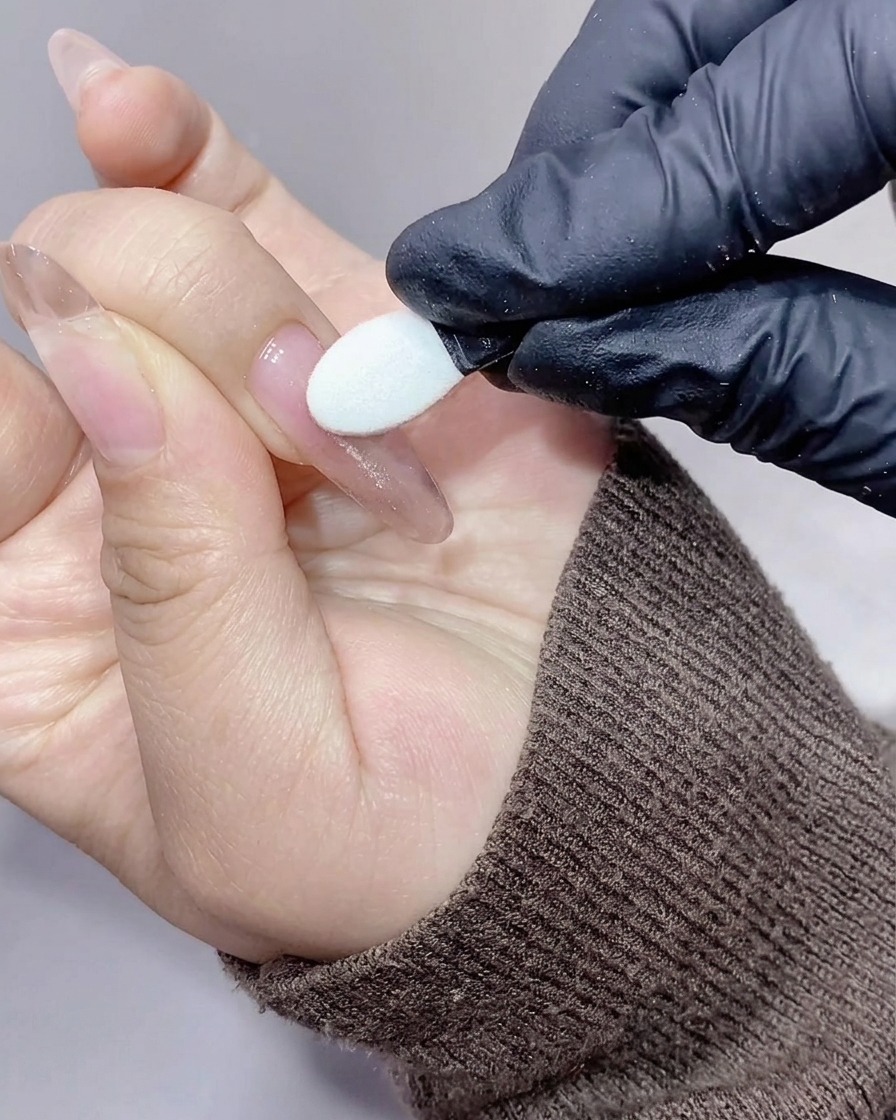 Un applicateur silicone frottant une poudre aurora iridescente sur la surface de longle.