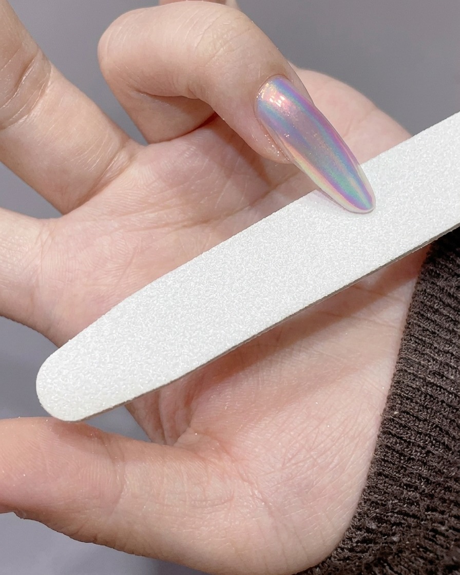 Une lime utilisée pour affiner le bord dun ongle long poudré au chrome.