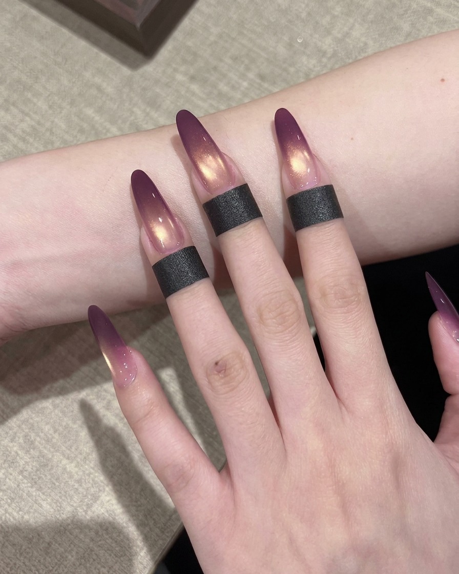 Un pinceau à ongles appliquant une couche de vernis gel cat-eye doré scintillant sur un ongle déjà doté dun dégradé ombré violet.