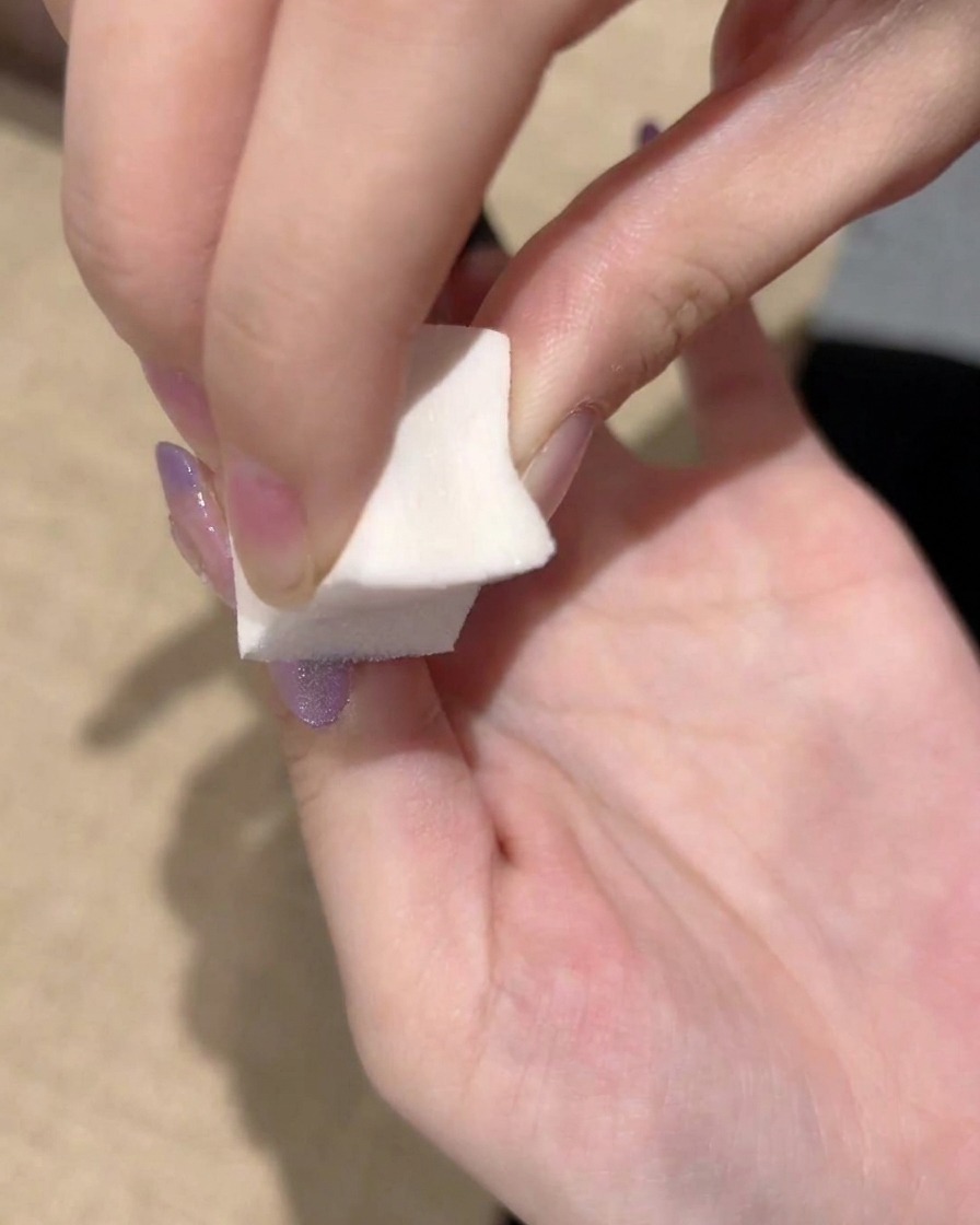 Gros plan sur une éponge tapotant répétitivement le bord du gel violet pour finaliser une transition de dégradé lisse.