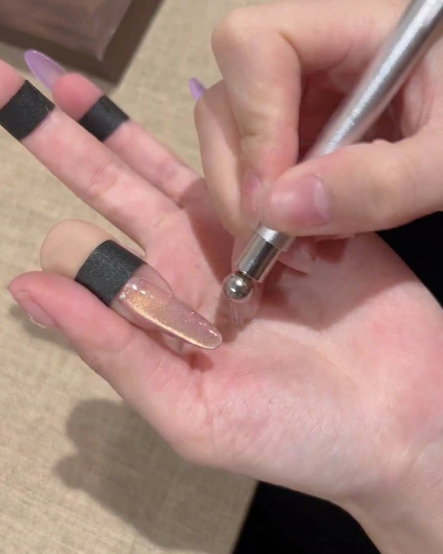 La pointe sphérique dun aimant créant un motif de tourbillon circulaire sur un ongle en gel cat-eye.