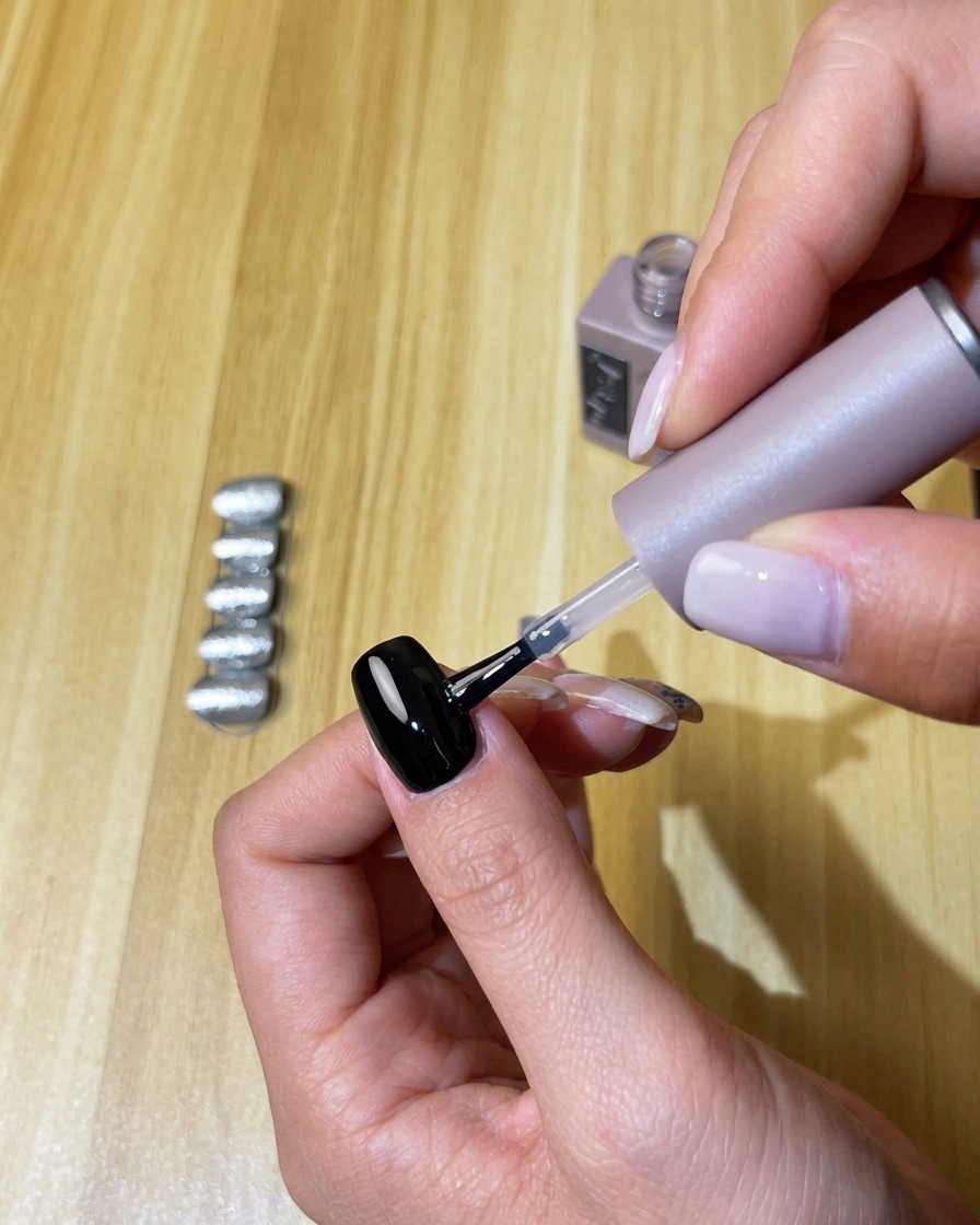 Application dune couche de top coat sans résidu sur longle en gel noir catalysé.