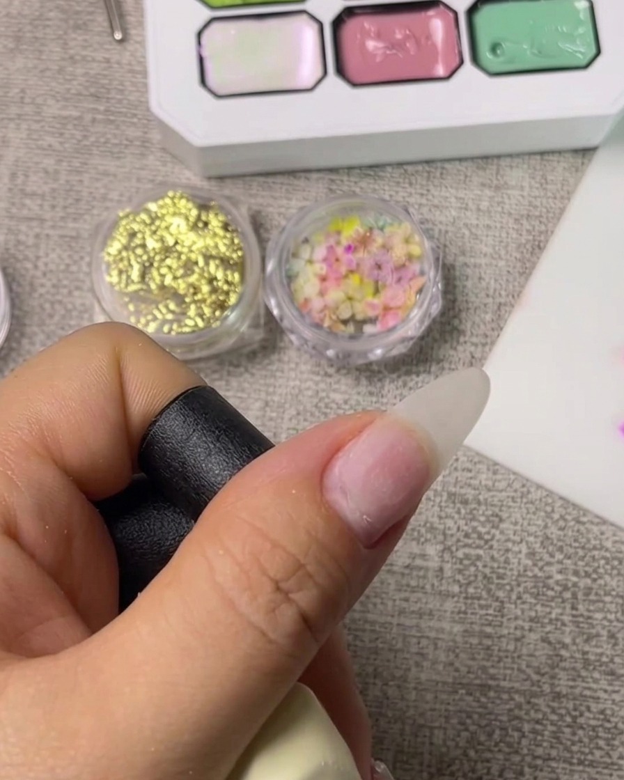 Gros plan sur un pinceau appliquant une base transparente sur un ongle naturel propre.