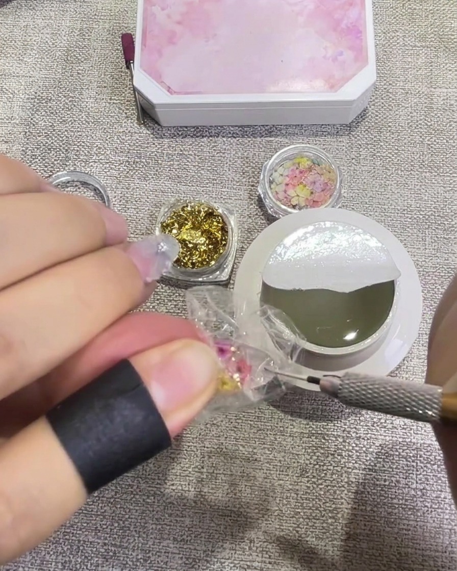 Un pinceau appliquant un top coat transparent brillant sur un ongle décoré.