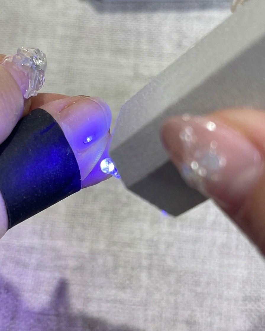 Une main décorée placée dans une lampe UV pour la catalysation finale.