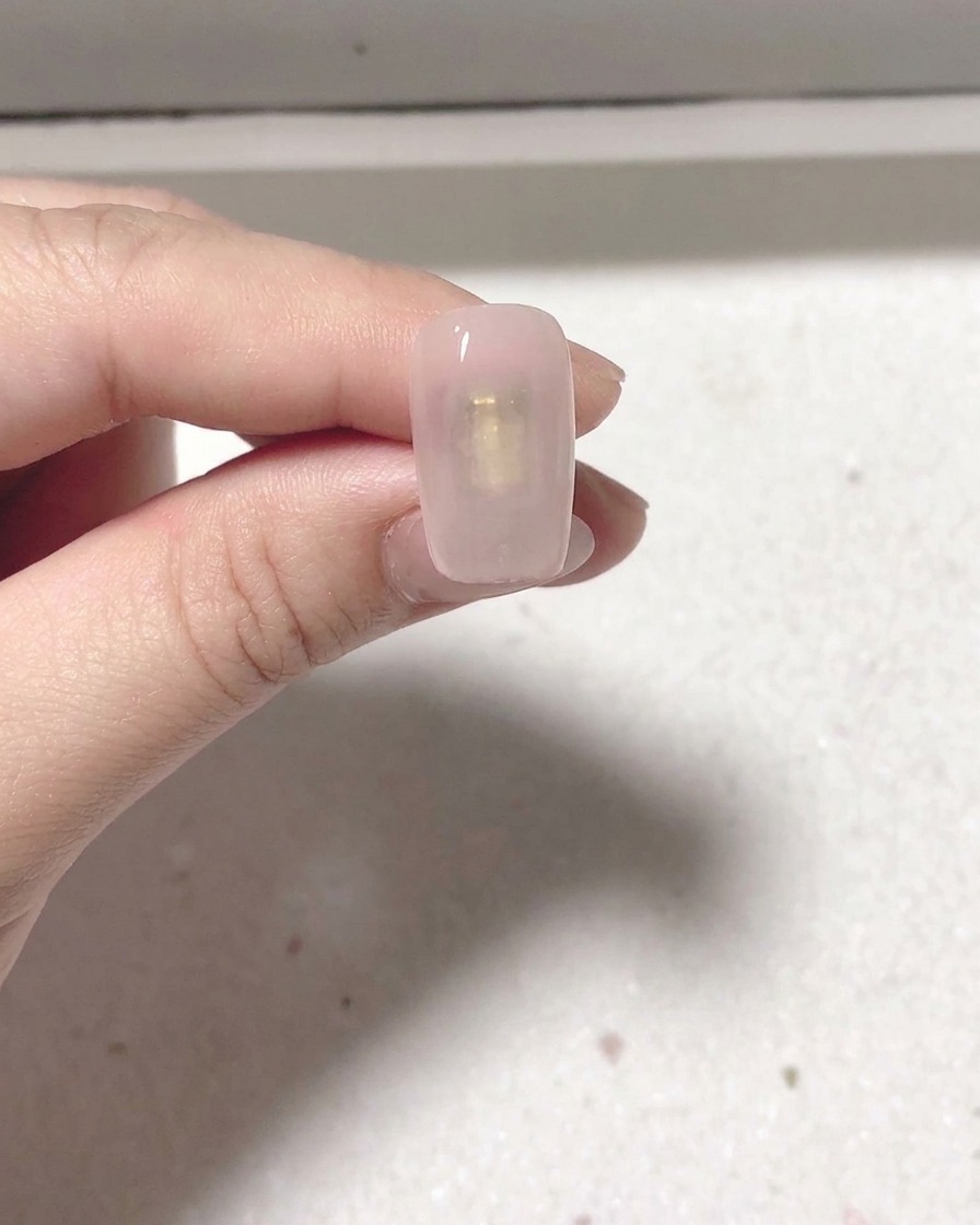 Un ongle manucuré placé sous une lampe professionnelle pour catalyser.