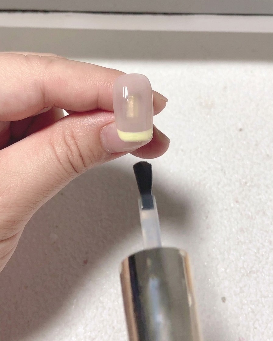 Un pinceau applique un top coat mat sur longle avec la french rouge.