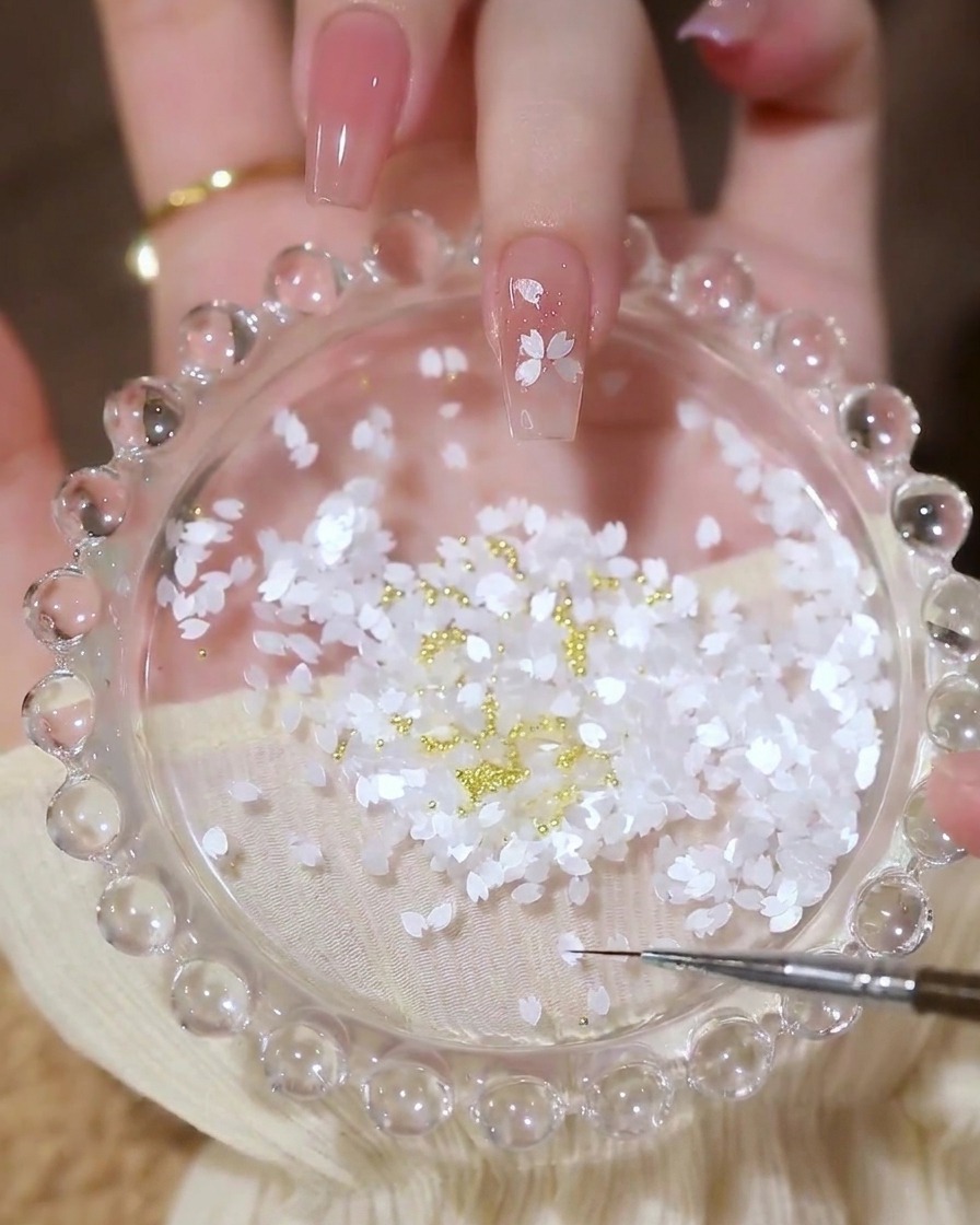 Ongle avec un motif floral terminé, composé de sequins pétale et dune perle dorée au centre.