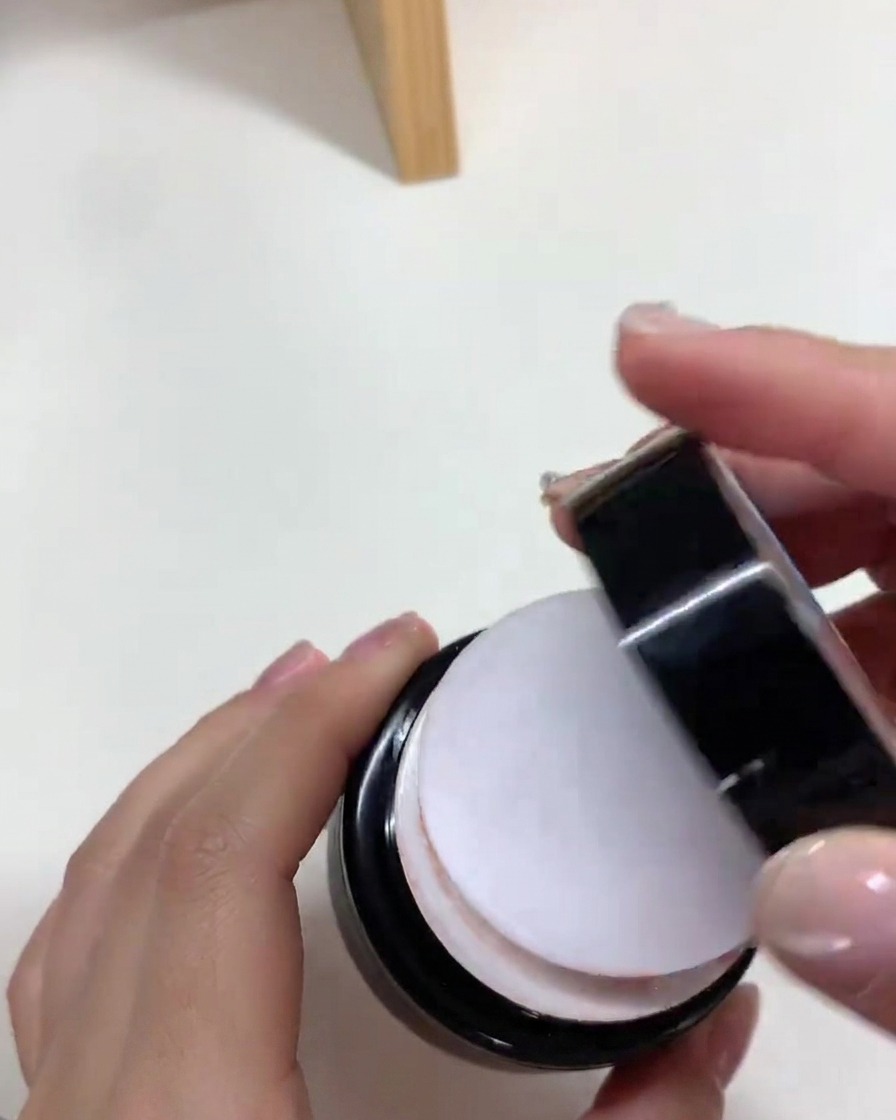 Un pinceau appliquant une couche uniforme de vernis gel nude sur une capsule dongle.