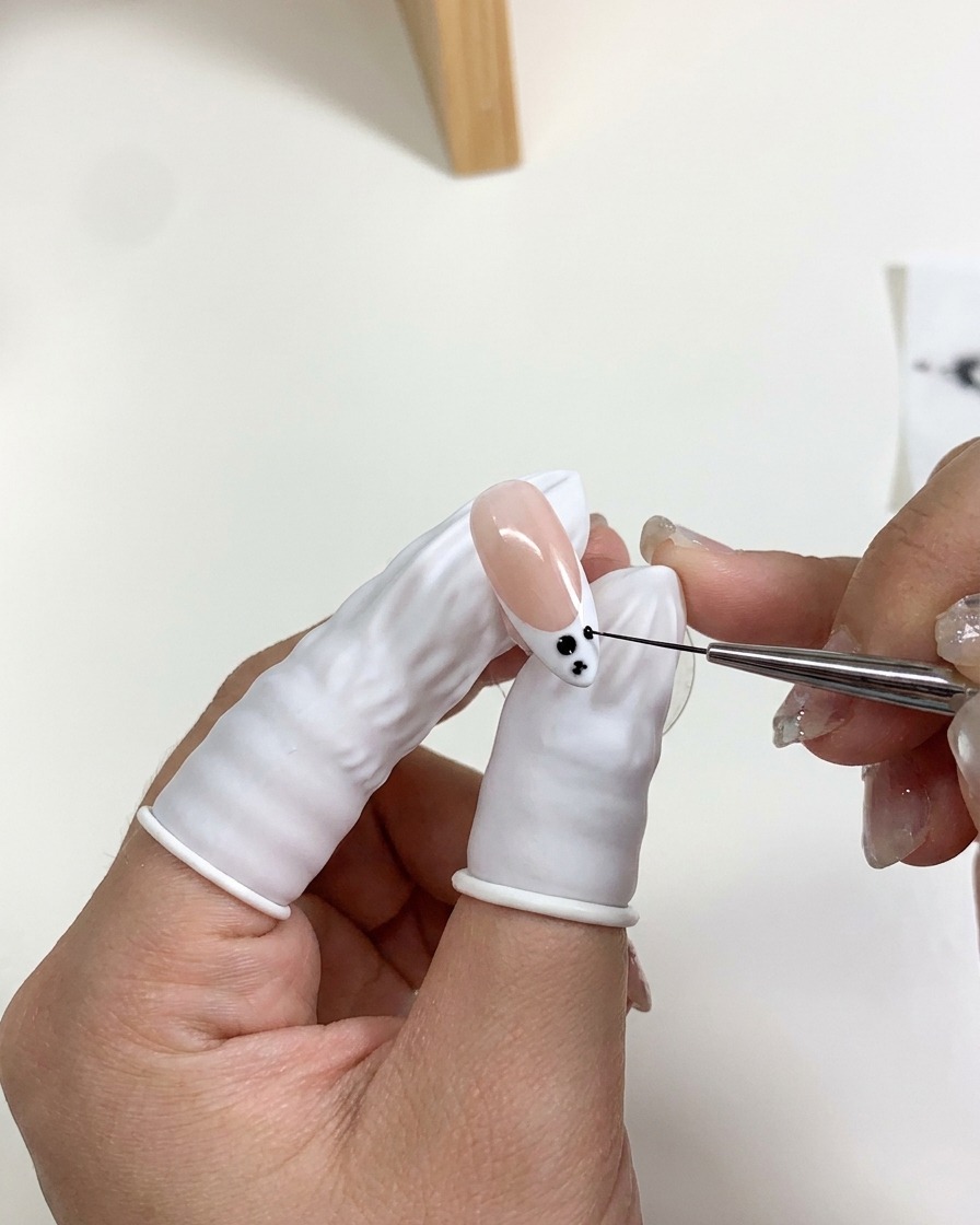 Gros plan sur des points de gel noir sétalant en un dégradé doux sur la French tip dun ongle.