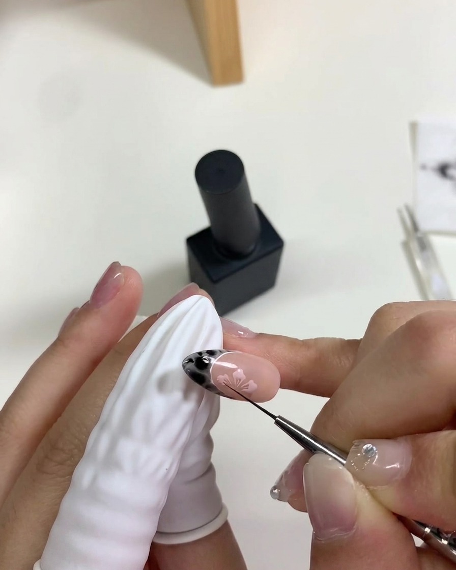Une main plaçant longle sous une lampe UV/LED portative pour catalyser les fleurs de cerisier en gel rose.
