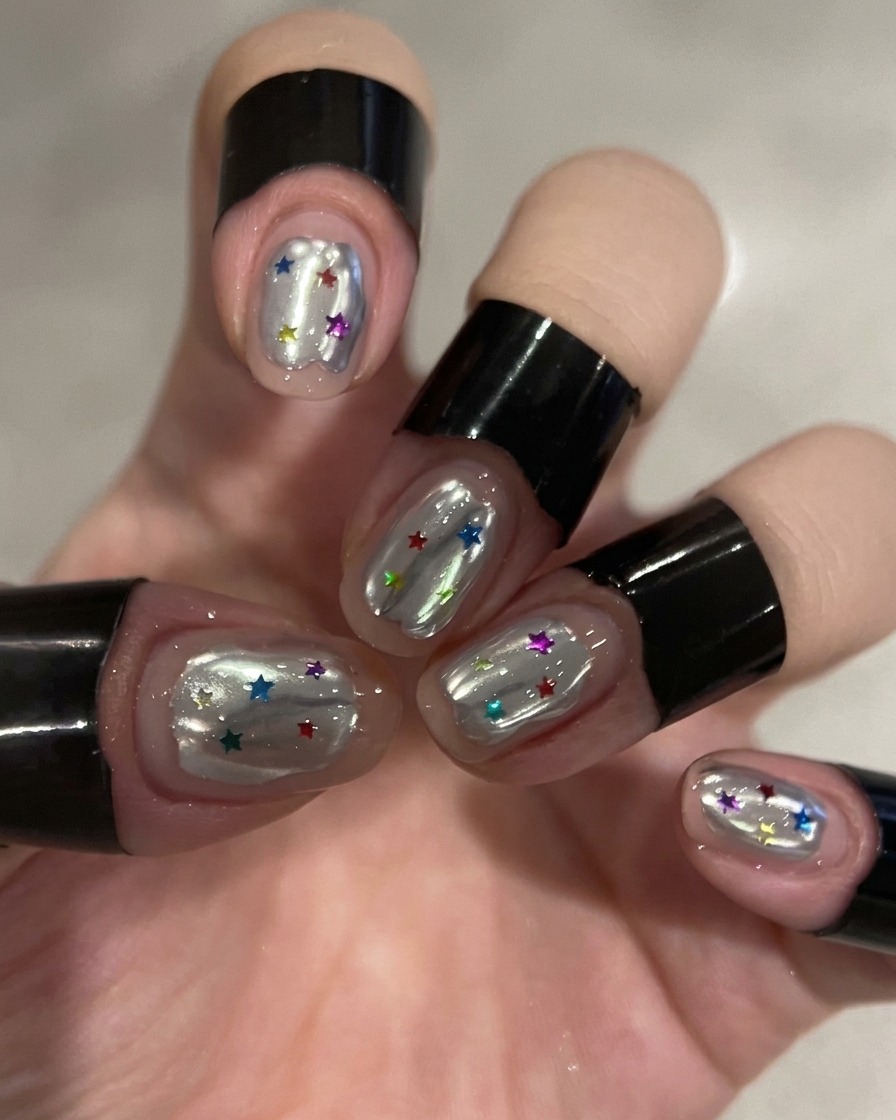 Un pinceau appliquant un top coat transparent sur un ongle chromé argenté.
