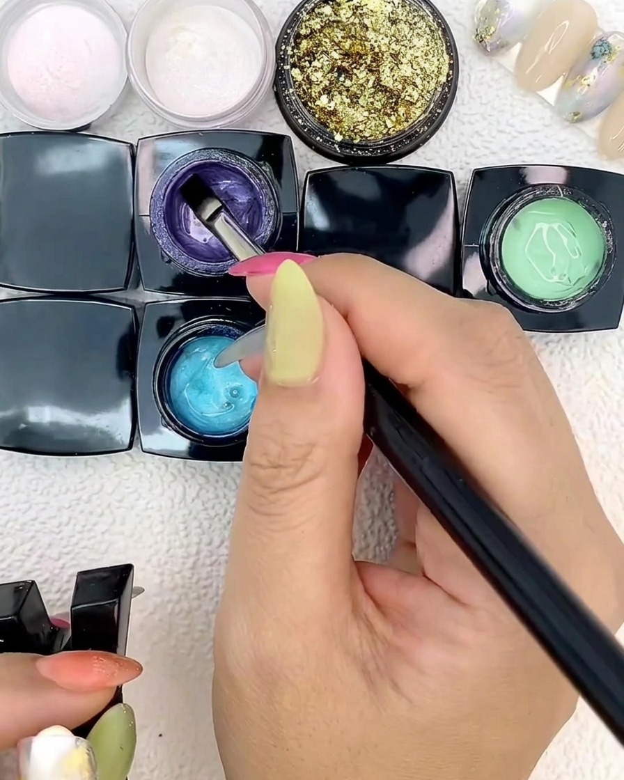 Un pinceau plat de nail art appliquant du gel bleu sur une capsule.