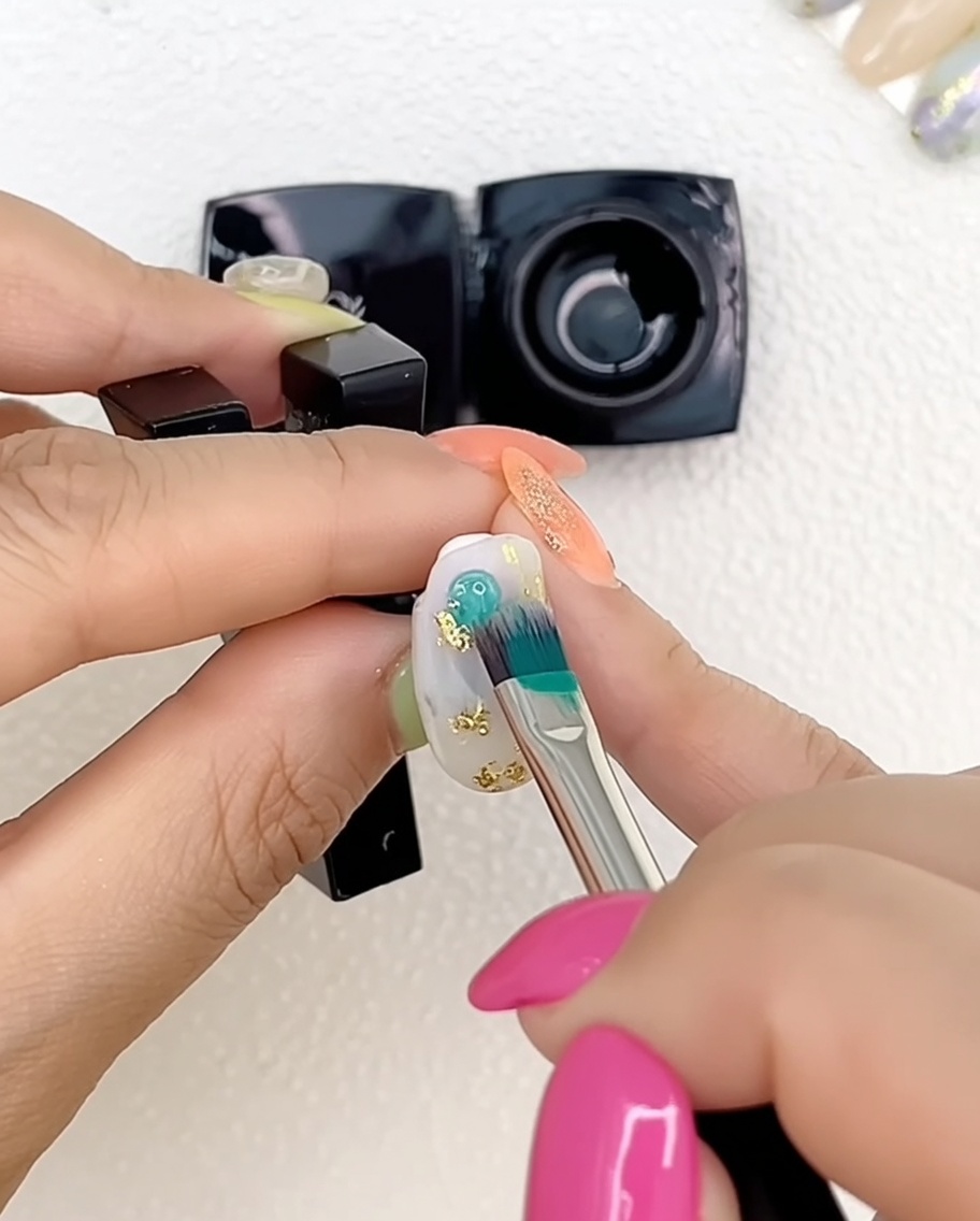 Un gros plan dune main avec des ongles peints au gel multicolore placés sous une lampe UV professionnelle pour catalyser.