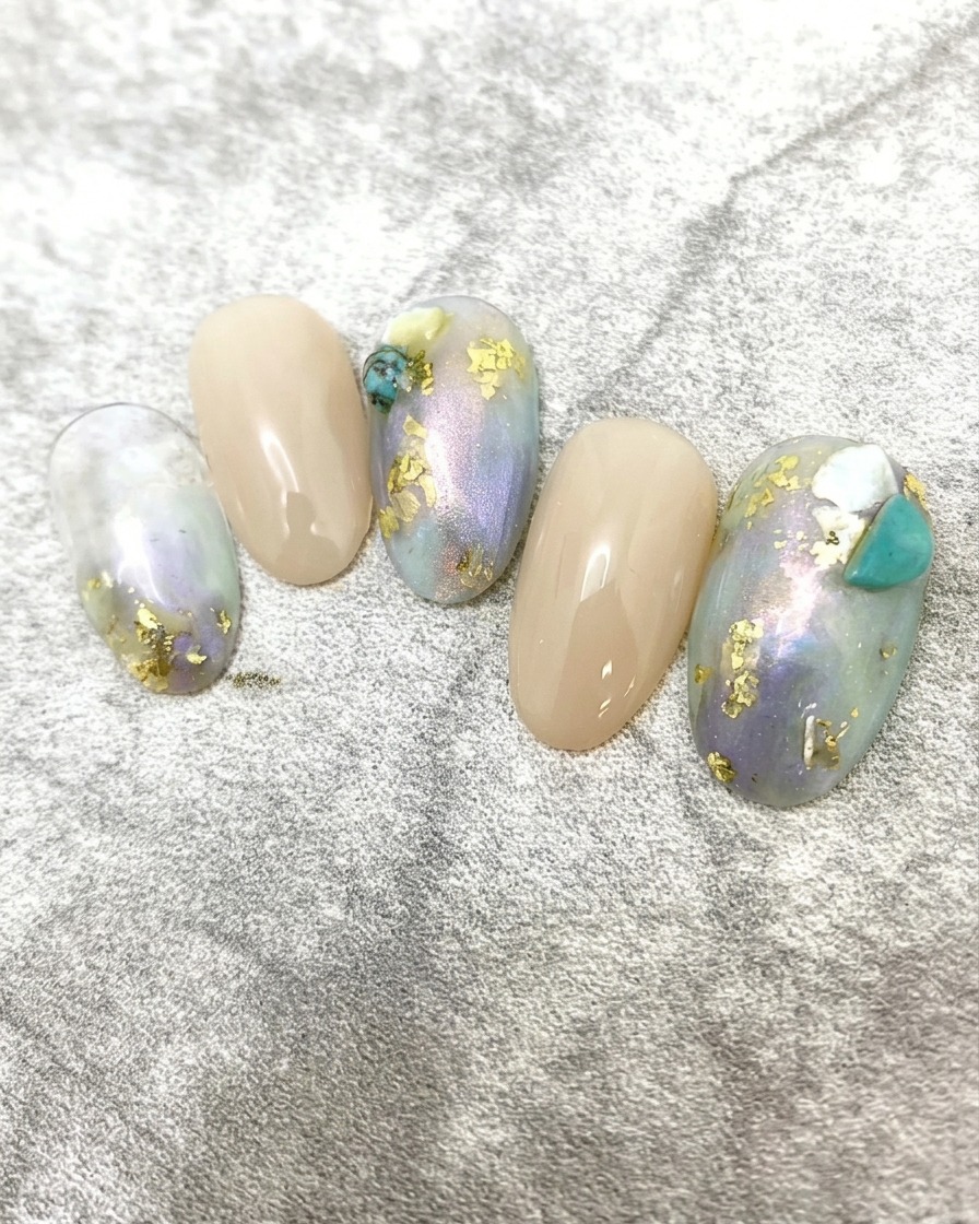 Un pinceau à ongles appliquant un top coat lisse et brillant sur un design dongles marbré et texturé.