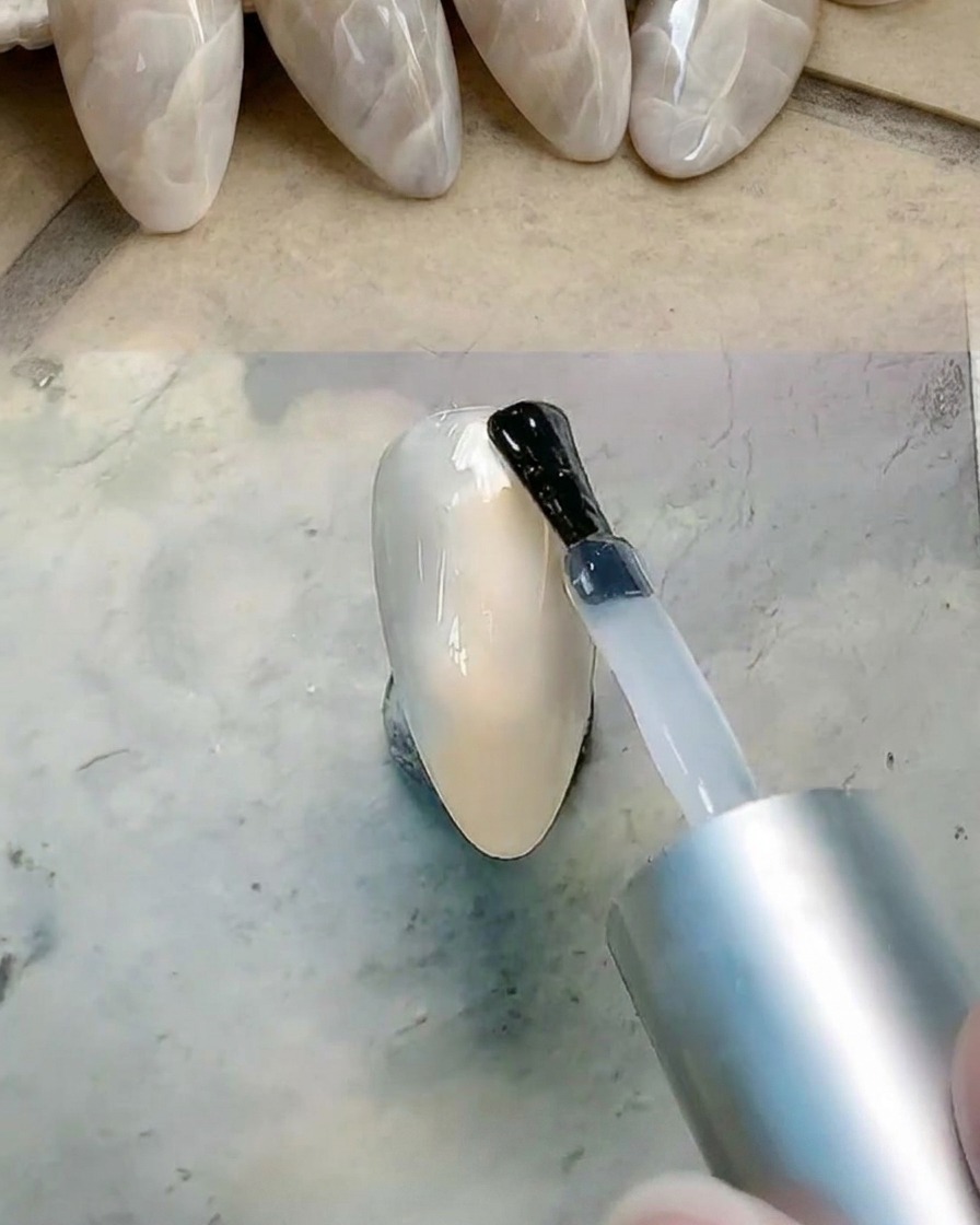 Pinceau appliquant une couche de gel transparent sur la surface de longle pour préparer le mélange.