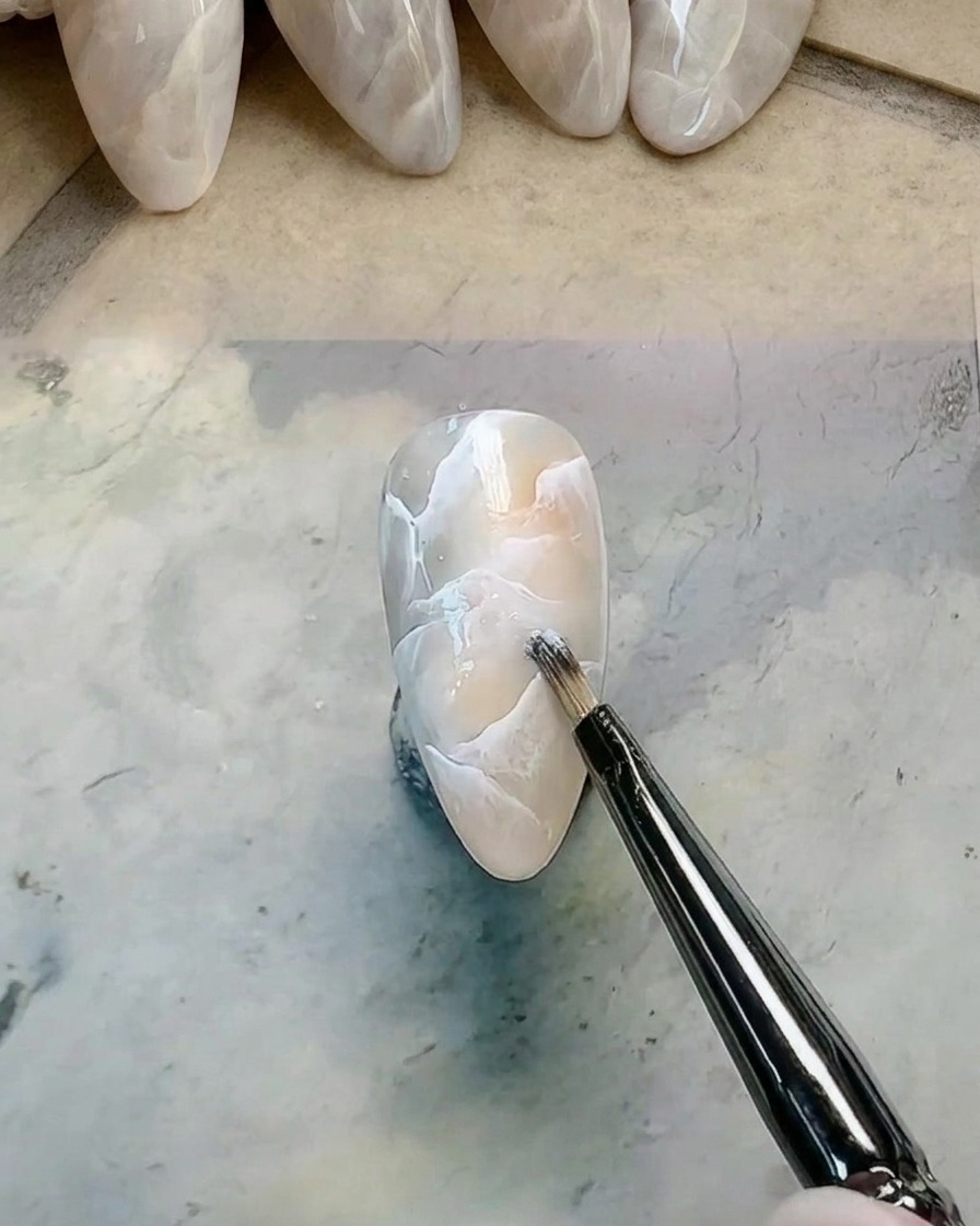 Pinceau de détail ajoutant et estompant du gel blanc supplémentaire sur le design.