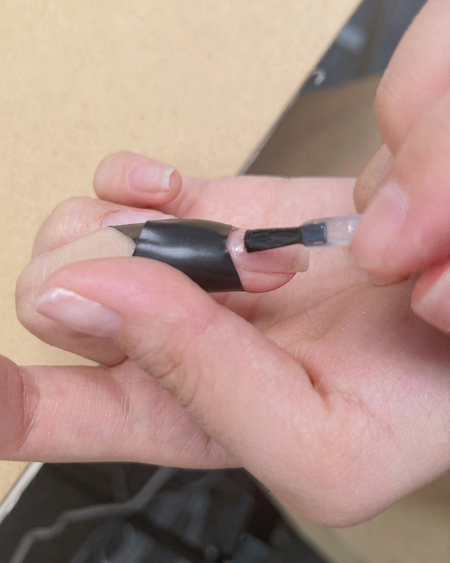Un pinceau appliquant une couche transparente et brillante de blooming gel sur une base nude.