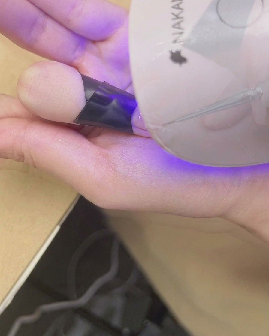 Un doigt placé sous une mini lampe UV/LED pour catalyser le dégradé blush terminé.