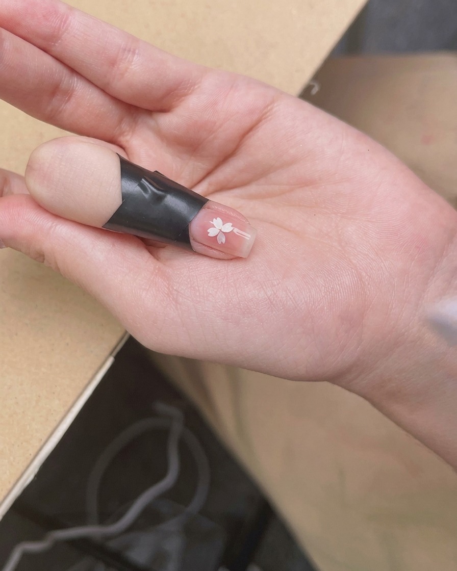 Une main positionnée sous une lampe à ongles UV/LED compacte, la lumière éclairant directement les ongles.