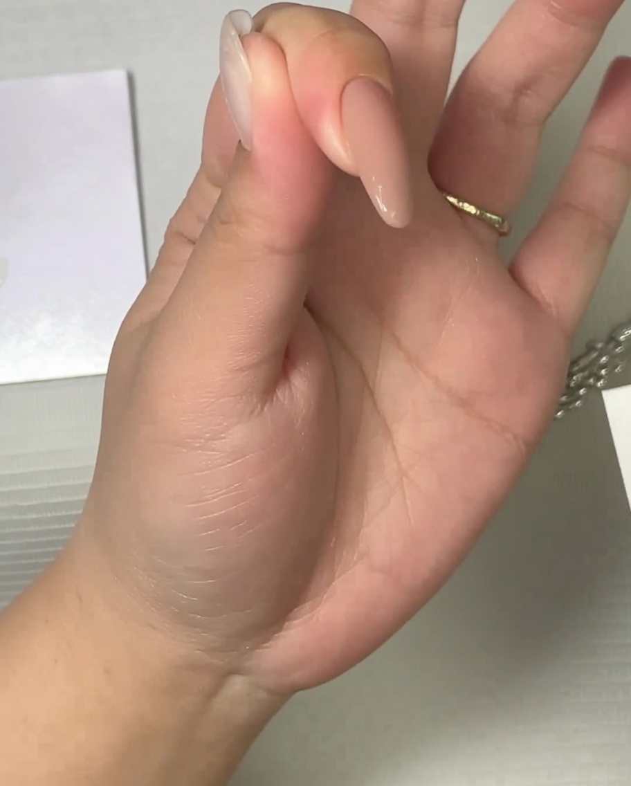 Un pinceau appliquant un top coat mat sur un ongle aux tons neutres.