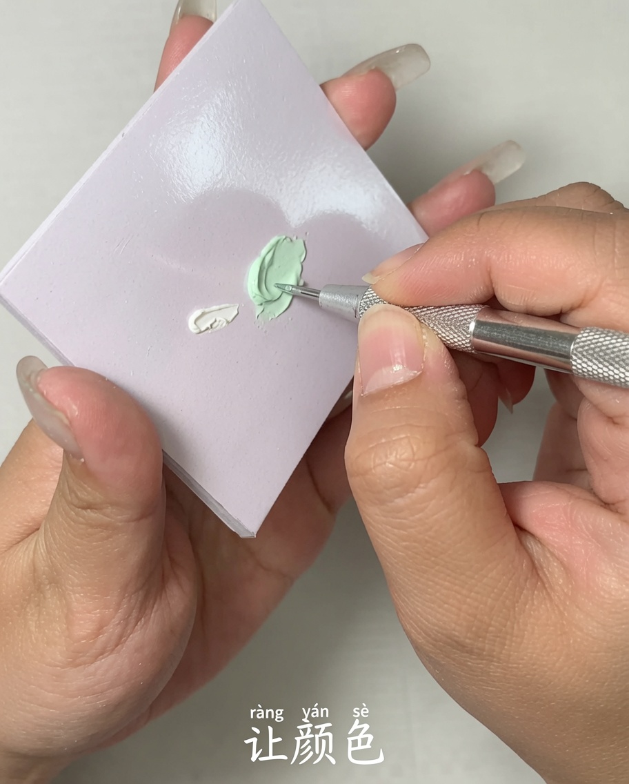 Gros plan dun outil en métal mélangeant deux couleurs de vernis gel sur une palette plate.